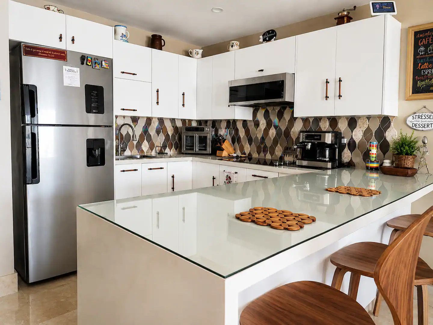 Cocina blanca con isla, taburetes y electrodomésticos de acero