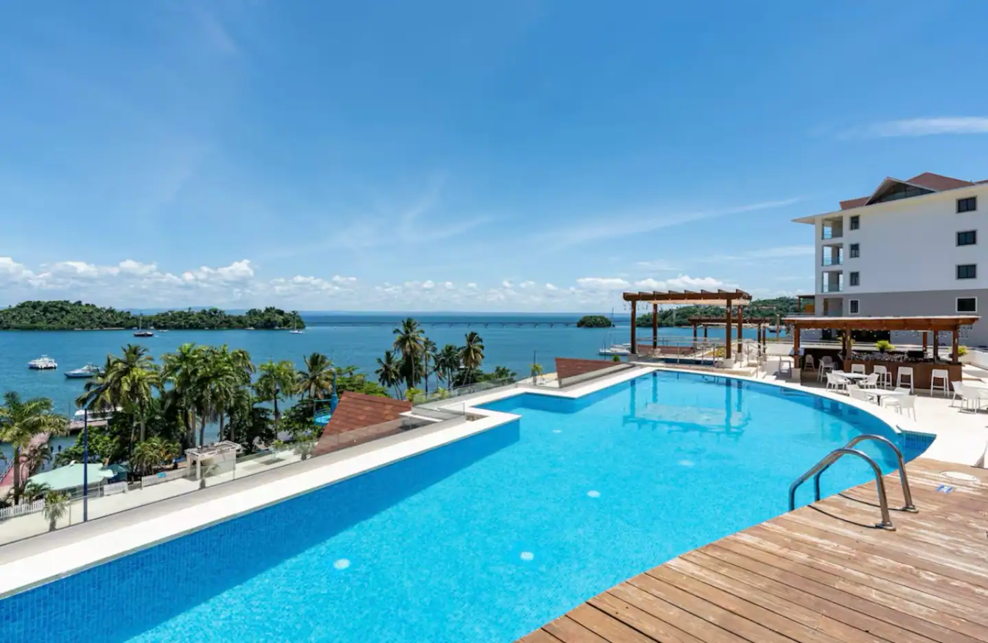 Piscina del complejo junto al mar, con tumbonas y palmeras