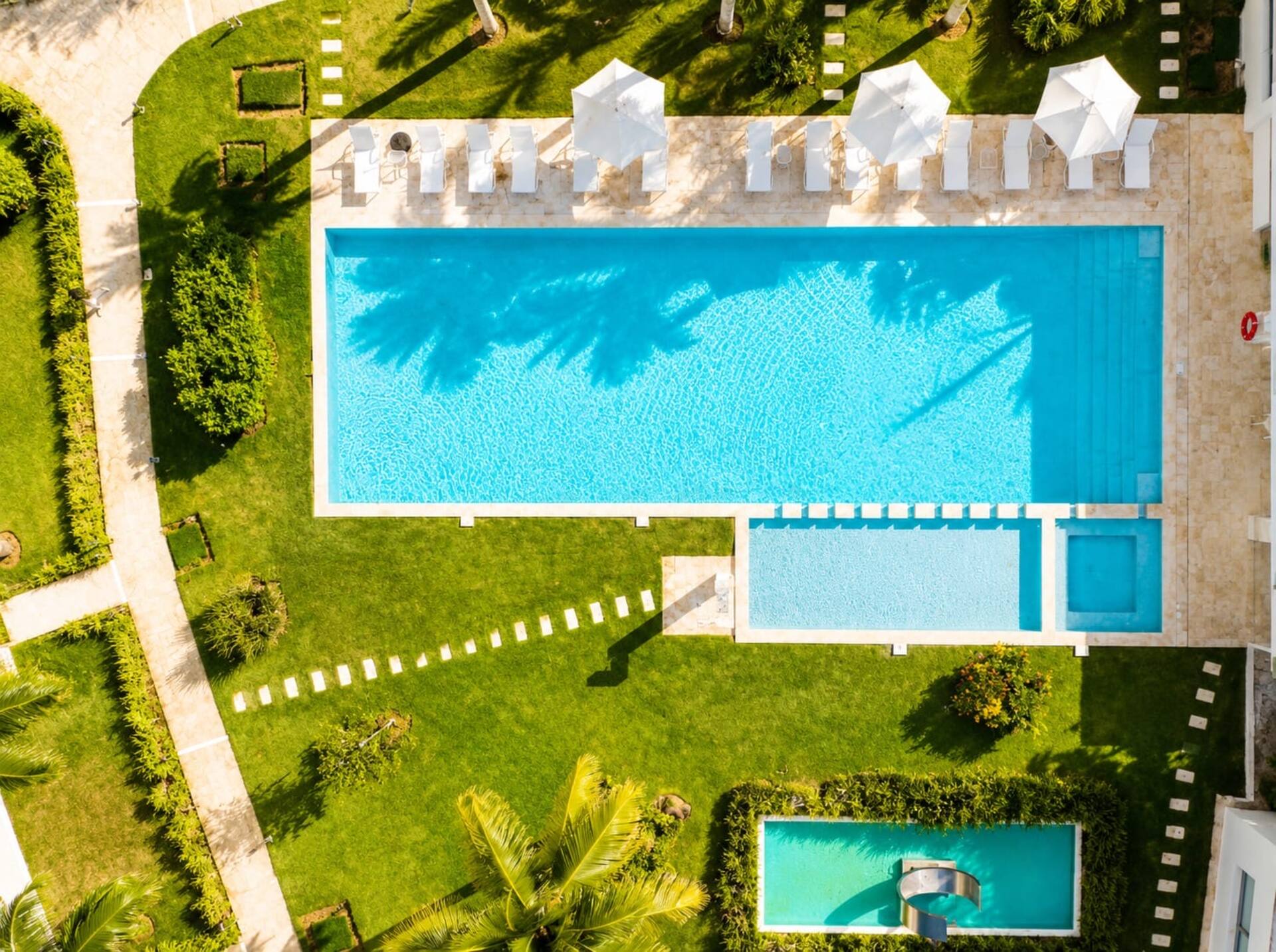 Piscina del complejo de Oasis Las Terrenas vista desde el aire, rodeada de césped y palmeras
