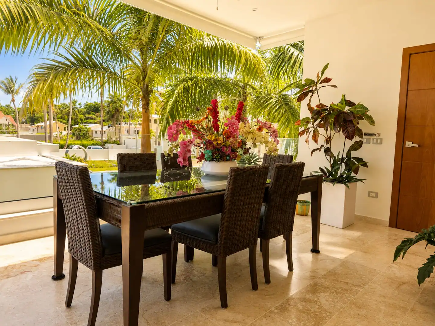 Comedor exterior con mesa de cristal, flores y vista al jardín