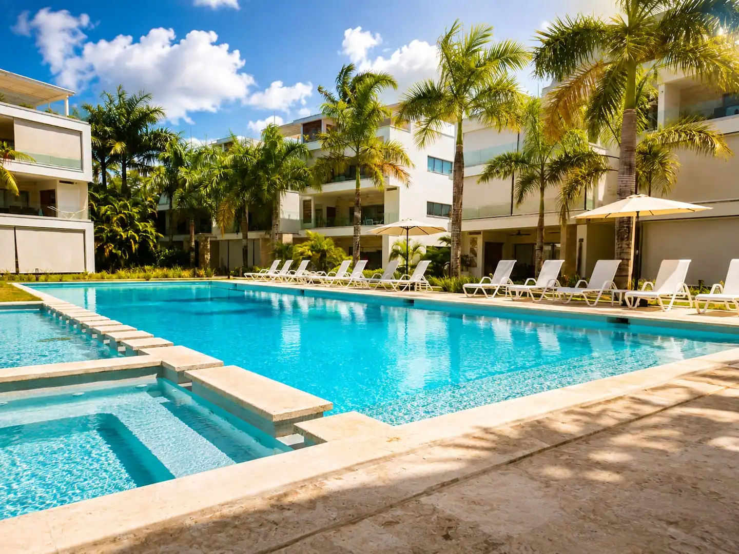 La piscina rodeada de palmeras y edificios blancos
